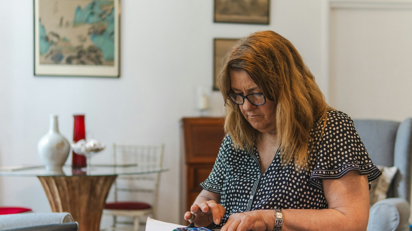 A woman at home working through bills and paperwork with a calculator
