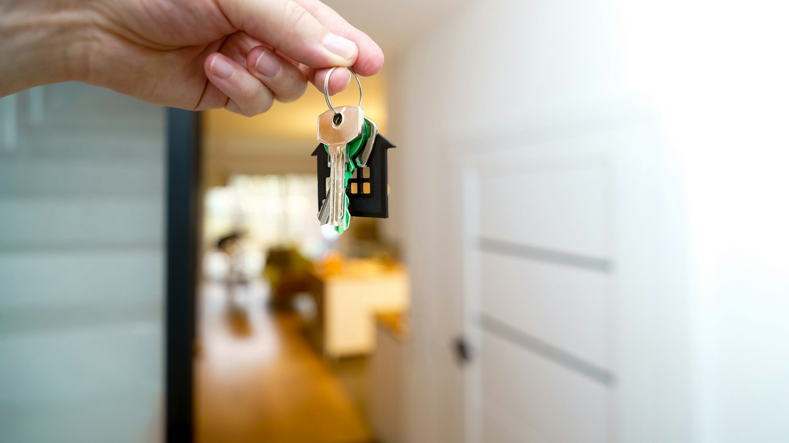 A hand holding a set of house keys inside a home