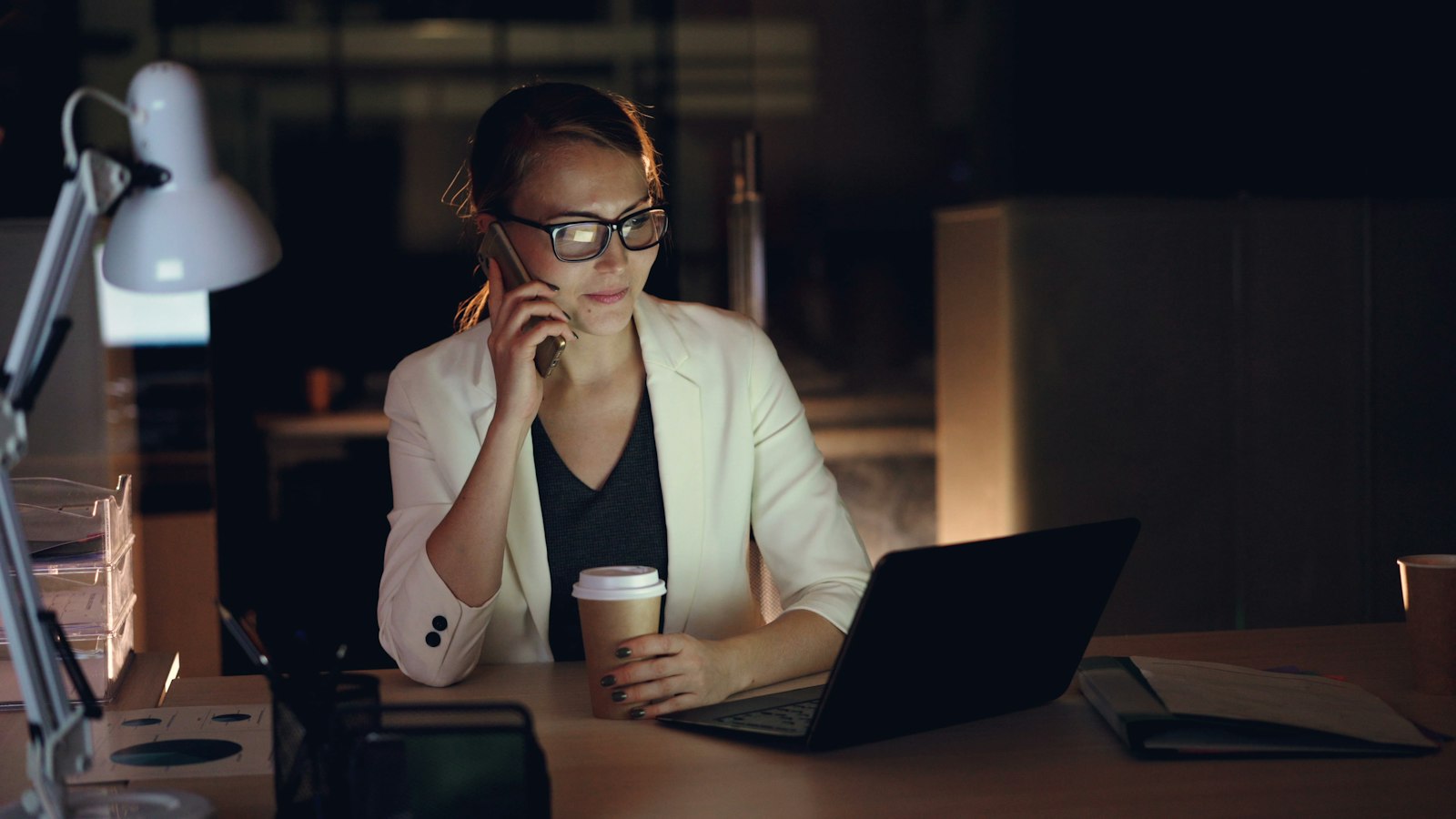 A lawyer on the phone at her desk late in the evening